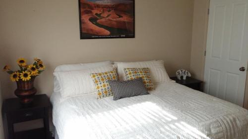 a bedroom with a white bed with pillows and a painting at Cedar Canyon Condos in Blanding