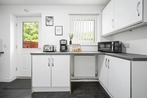 a kitchen with white cabinets and a black counter top at Stunning Entire House 6 mins to Manchester City Centre, near Etihad stadium, Free Parking and Super Fast Wifi in Manchester