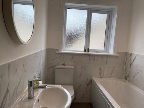 a bathroom with a sink and a tub and a window at Walton House in Frinton-on-Sea
