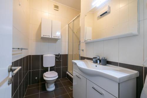 a bathroom with a white toilet and a sink at Bugenvilija apartment in Brna