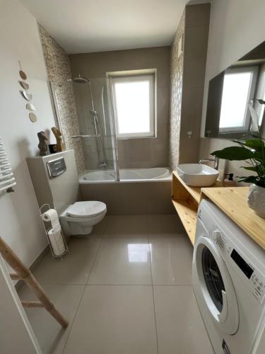 een badkamer met een toilet, een wastafel en een wasmachine bij Apartament BohoLook in Nowy Sącz