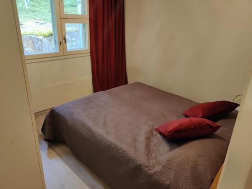 a bed with two red pillows sitting next to a window at Saimaan Kodikas in Savonlinna