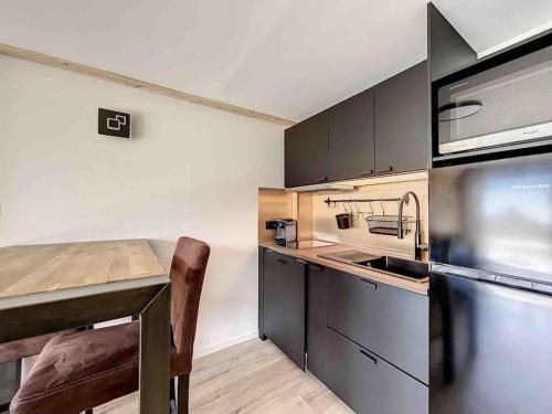 a kitchen with a table and a sink and a refrigerator at Petit loft chaleureux et cosy - vue montagne in Guillestre