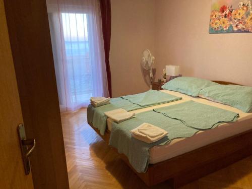 耶塞尼采的住宿－Toni&Megi Apartment，一间卧室配有一张带绿色床单的床和一扇窗户。