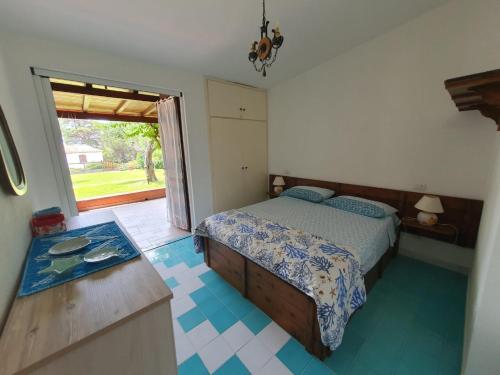a bedroom with a bed and a kitchen with a window at Villa ValePina in Villasimius