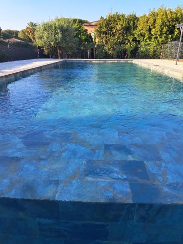 une piscine avec de l'eau bleue dans une cour dans l'établissement Cottage 43 m2 2 épis - Plage à 400m - PARKING Jardin TERRASSE Wifi, à Six-Fours-les-Plages