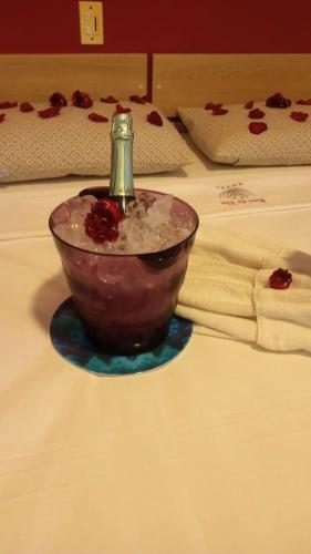a glass bowl with a bottle in it on a bed at Hotel Rosa da Ilha Guaruja - Perto do Mar com piscina in Guarujá