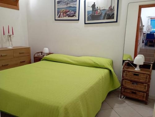a bedroom with a green bed and pictures on the wall at Favignana Vacanze in Favignana
