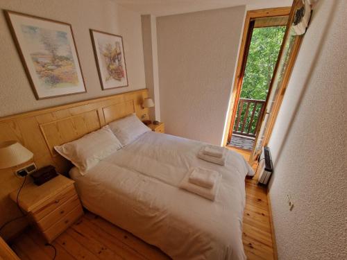 um quarto com uma cama com lençóis brancos e uma janela em Apartamento acogedor con vistas em Taull