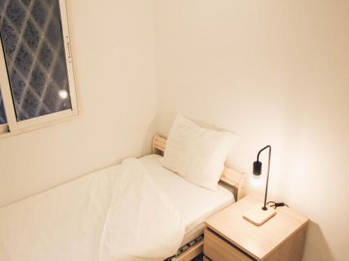 a small room with a bed and a lamp on a night stand at Apartamento 15' Barcelona centro in Santa Coloma de Gramanet