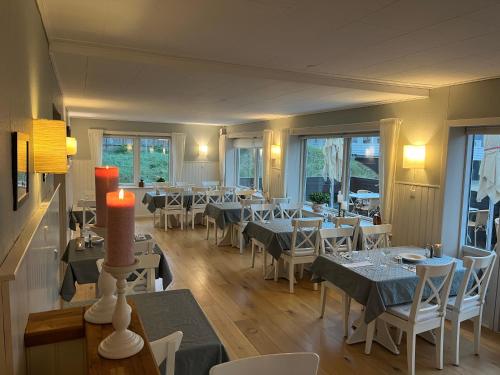 un restaurante con mesas, sillas blancas y ventanas en Klithjem Badehotel en Vejers Strand