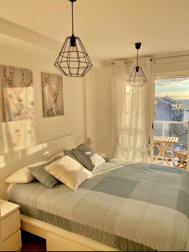 a bedroom with a bed and two pendant lights at Apartamentos LAMAROSA -PLAYA URBANA in Burela de Cabo