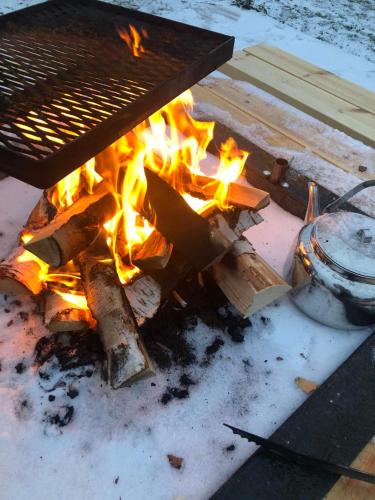 a fire pit with a grill and flames at The Northern Light Apartment in Jukkasjärvi