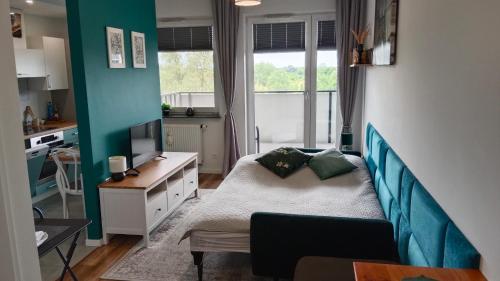 a bedroom with a bed and a desk and a kitchen at Apartament zielony in Konin
