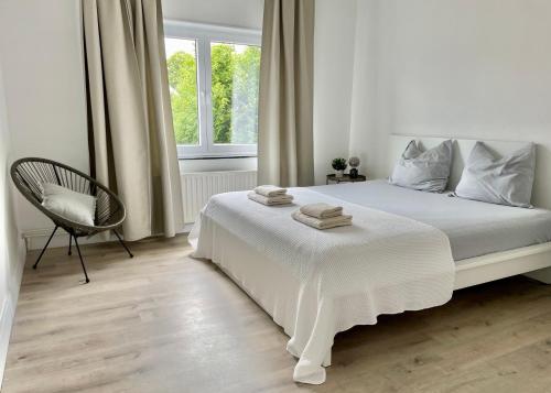 a white bedroom with a white bed and a chair at Sfeer in Maaseik