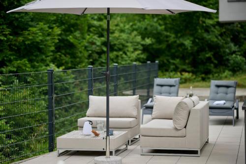 a group of chairs and an umbrella on a patio at Design Apartment mit Panoramafenster & Naturblick - KLIMATISIERT in Bregenz