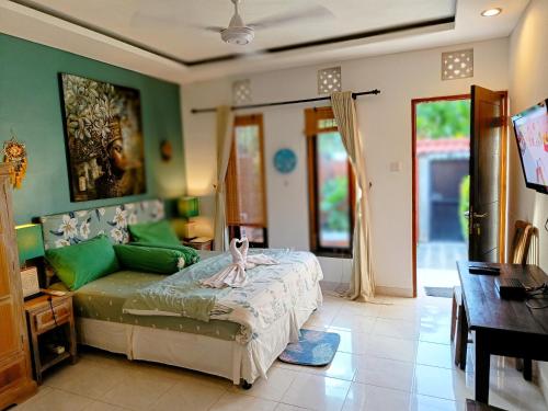 a bedroom with a bed with green walls and a table at Merpati - Studios in Sanur