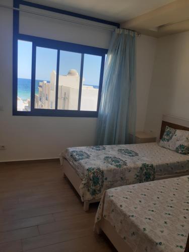 a bedroom with two beds and a large window at Dar Bhar in Kelibia