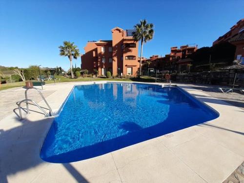 a large blue swimming pool in front of a building at Apartamento de dos dormitorios y un baño con piscinas y jardines cercano a la playa in Estepona