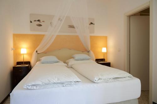 1 Schlafzimmer mit 2 Betten mit weißer Bettwäsche und 2 Lampen in der Unterkunft Villa Cartoceto in Cartoceto