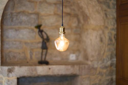 a light bulb hanging from a brick wall at La ferme de Roquedure in Montfaucon