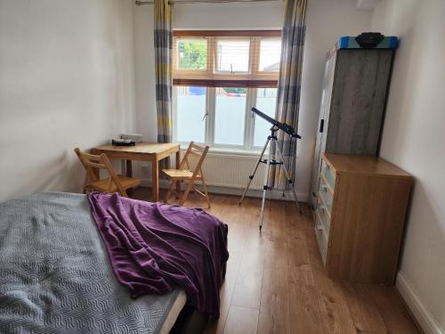 a bedroom with a bed and a table and a window at Countryside Home in London in Shirley