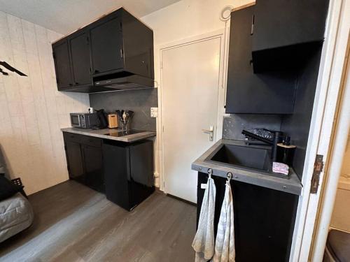 małą kuchnię z czarnymi szafkami i zlewem w obiekcie Studio Guzet-Neige, au pied des pistes w mieście Ustou