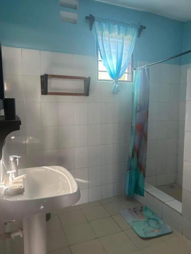 La salle de bains est pourvue d'un lavabo et d'une douche. dans l'établissement Bedroom Diani Beach, à Junda