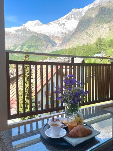 a table with a tray of food and flowers on a balcony at Victoria's Home - luxurious penthouse in Saas-Fee