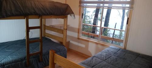 Recinto的住宿－Cabañas el Mirador，一间卧室配有双层床和窗户。