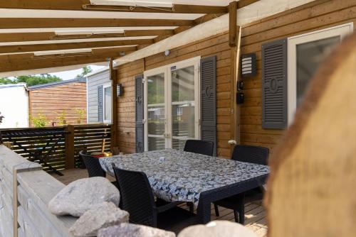patio ze stołem i krzesłami na tarasie w obiekcie Grand Mobil Home 6 personnes climatisé avec 3 chambres et 2 salles de bains à Munster en Alsace w mieście Munster