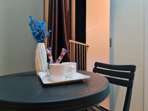 a black table with two coffee cups and a vase with flowers at Resting View in Male City