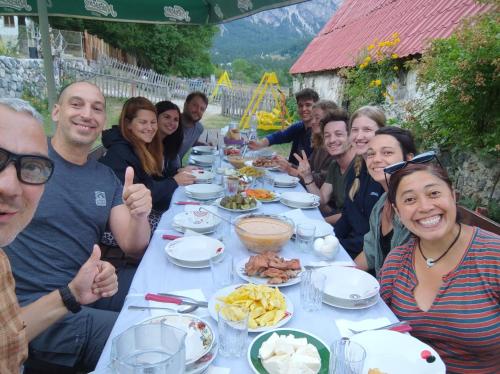a group of people sitting at a table with food at Kulla e Sadri Lukes in Theth