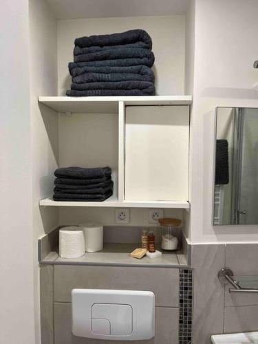 une salle de bain avec une étagère avec des serviettes et un miroir dans l'établissement Duplex bord de mer La Madrague, à Marseille