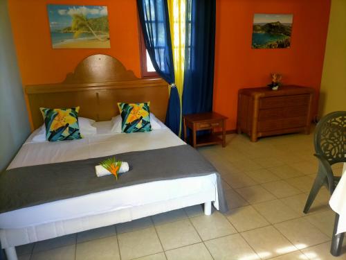 een slaapkamer met een bed met een oranje muur bij ISK LOCATION in Sainte-Rose