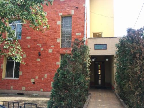 a red brick building with two trees in front of it at Pensiunea Casa Raul in Cluj-Napoca