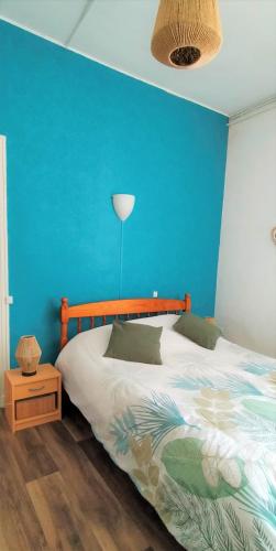 une chambre avec un lit avec un mur bleu dans l'établissement Mesnil Val Plage, à Criel-sur-Mer