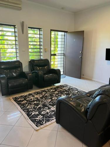 a living room with black leather furniture and a rug at Garden Apartments in Nadi