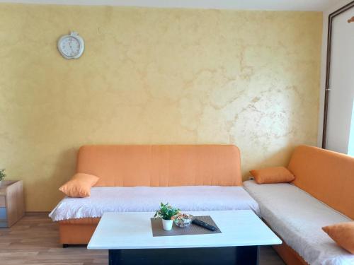 una camera con due letti, un tavolo e un orologio di APARTMAN LALA a Foča
