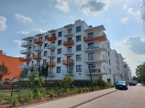 una macchina blu che passa davanti a un grande edificio bianco di LuxApartmentWarszawa z bezpłatnym podziemnym parkingem a Varsavia