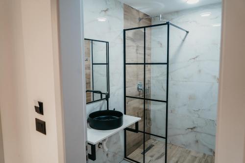 een badkamer met een glazen douche en een wastafel bij The Barrels Ms in Gjirokastër