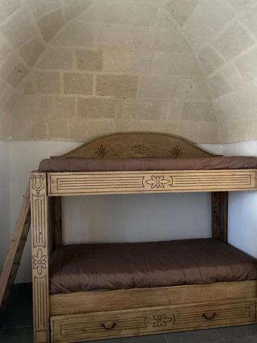a wooden bunk bed with a brown cushion on it at Salenti..amo in Pulsano