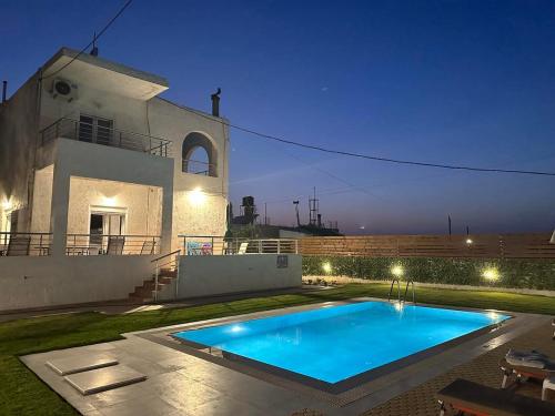 a swimming pool in front of a house at night at Amazing Villa Chrysanthi with private pool in Heraklion in Epáno Váthia