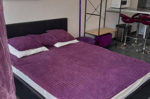 - un lit avec une couette et des oreillers en violet dans l'établissement Studio 77, Héliopolis L au village naturiste, au Cap d'Agde
