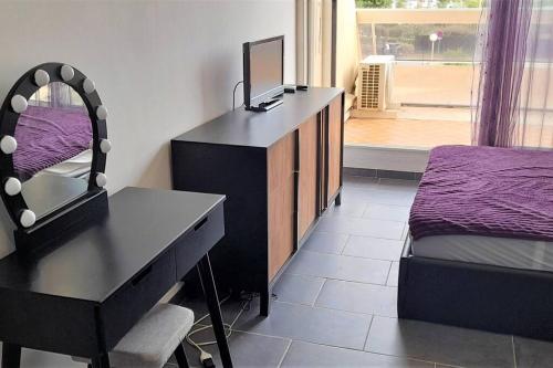 - une chambre avec un bureau, un lit et un miroir dans l'établissement Studio 77, Héliopolis L au village naturiste, au Cap d'Agde