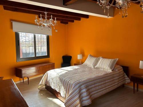 1 dormitorio con paredes de color naranja, 1 cama y ventana en Departamento en Vistalba, Lujan con vista a la Montaña en Luján de Cuyo