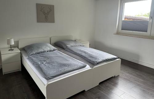 a white bed in a room with a window at Moderne Ferienwohnung mit Terrasse in Guxhagen