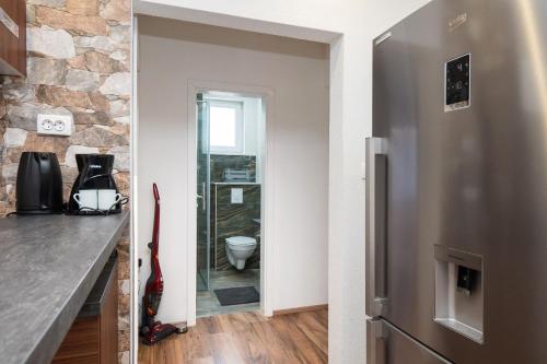 a kitchen with a stainless steel refrigerator and a stone wall at Apartment Nikita with Pool in Zaboric