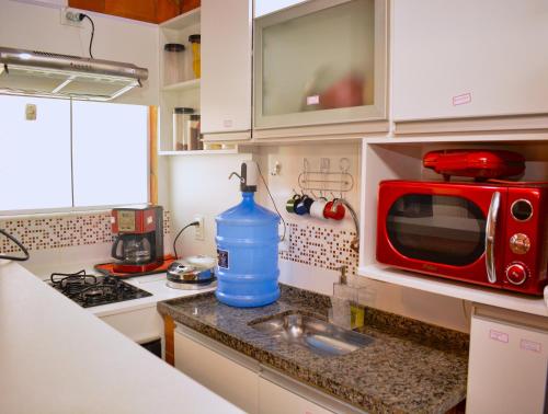 a kitchen with a red microwave and a blue water bottle at Barra da Tijuca Rio de Janeiro ilha da gigoia in Rio de Janeiro