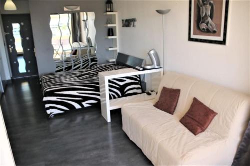 un salon avec un canapé blanc et un bureau avec un ordinateur portable dans l'établissement Studio 321, Héliopolis AB au village naturiste, au Cap d'Agde